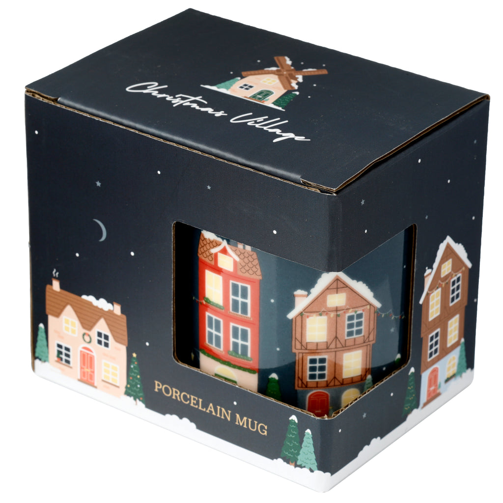 Angled view of a Christmas Village porcelain mug in its dark blue packaging. The box has a cut-out window, revealing the mug's festive design of colourful snow-covered houses and trees. The packaging itself features a winter village illustration and the text 'PORCELAIN MUG'.