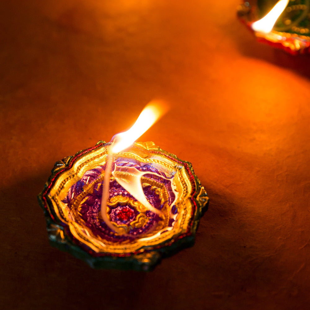 Decorative candle in a metal holder with a flame on a dark background