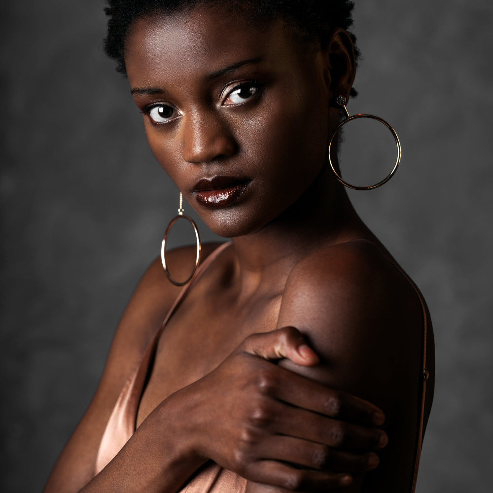 Woman with large hoop earrings and a dark background