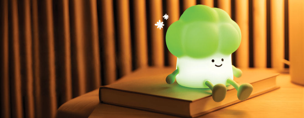 Green broccoli-shaped night light on a book with a warm background