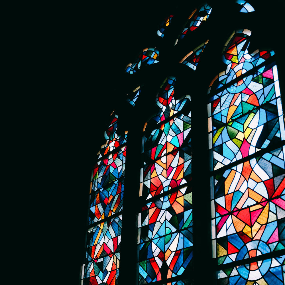Stained glass windows with colorful geometric patterns against a dark background