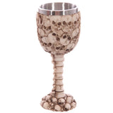 Full view of a decorative multi skull and spine goblet, featuring a textured, bone-coloured exterior covered in skulls, a spinal column stem, and a silver-coloured metallic lining.