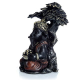 Black and gold Ganesh ornament seated under a tree, with an intricate gold crown and holding a bowl of golden offerings.