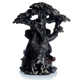 Black and gold Ganesh figurine, angled view, showing a textured tree trunk and foliage with the Ganesh figure partially obscured behind it.