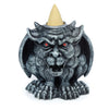 Front view of a dark grey, stone-effect gargoyle incense burner with red eyes. A light beige incense cone rests on its head.