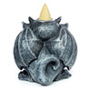 Rear view of a dark grey gargoyle backflow incense burner, featuring textured, folded wings and a light-coloured incense cone in a metal holder on its top.