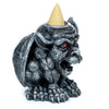 Angled view of a dark grey gargoyle-shaped incense burner with a stone effect finish, featuring red eyes, a snarling mouth, and a light-coloured cone incense placed on its head.