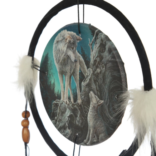 Close-up of a Guidance Wolf dreamcatcher, with a detailed illustration of a large grey wolf standing on a rock looking towards a smaller wolf cub below, set against a dark forest and blue sky. It features a black hoop, white feathery embellishments, and wooden beads.