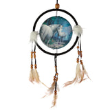 Front view of a dreamcatcher with a black-wrapped hoop, featuring a circular illustration of two white unicorns in a mystical blue-green forest, adorned with white fluffy tufts, wooden beads, and natural-coloured feathers.