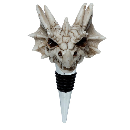 Front view of a pale, bone-coloured dragon skull bottle stopper with dark brown eyes and horns, featuring a metallic stem with black rubber rings.