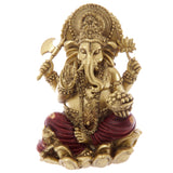 Front view of a gold and red Ganesh statue, depicting the elephant-headed deity seated with four arms holding an axe, lotus flower, and a bowl of sweets. The figurine features intricate gold details and red robes.