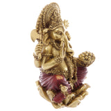 Angled view of a gold and red Ganesh statue, showcasing intricate golden details on its crown and jewellery, alongside red draped clothing, holding an axe and a bowl of sweets.