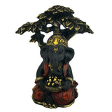 Front view of a black and gold Ganesh figurine, seated under a tree, adorned with red robes and holding a bowl of golden items.