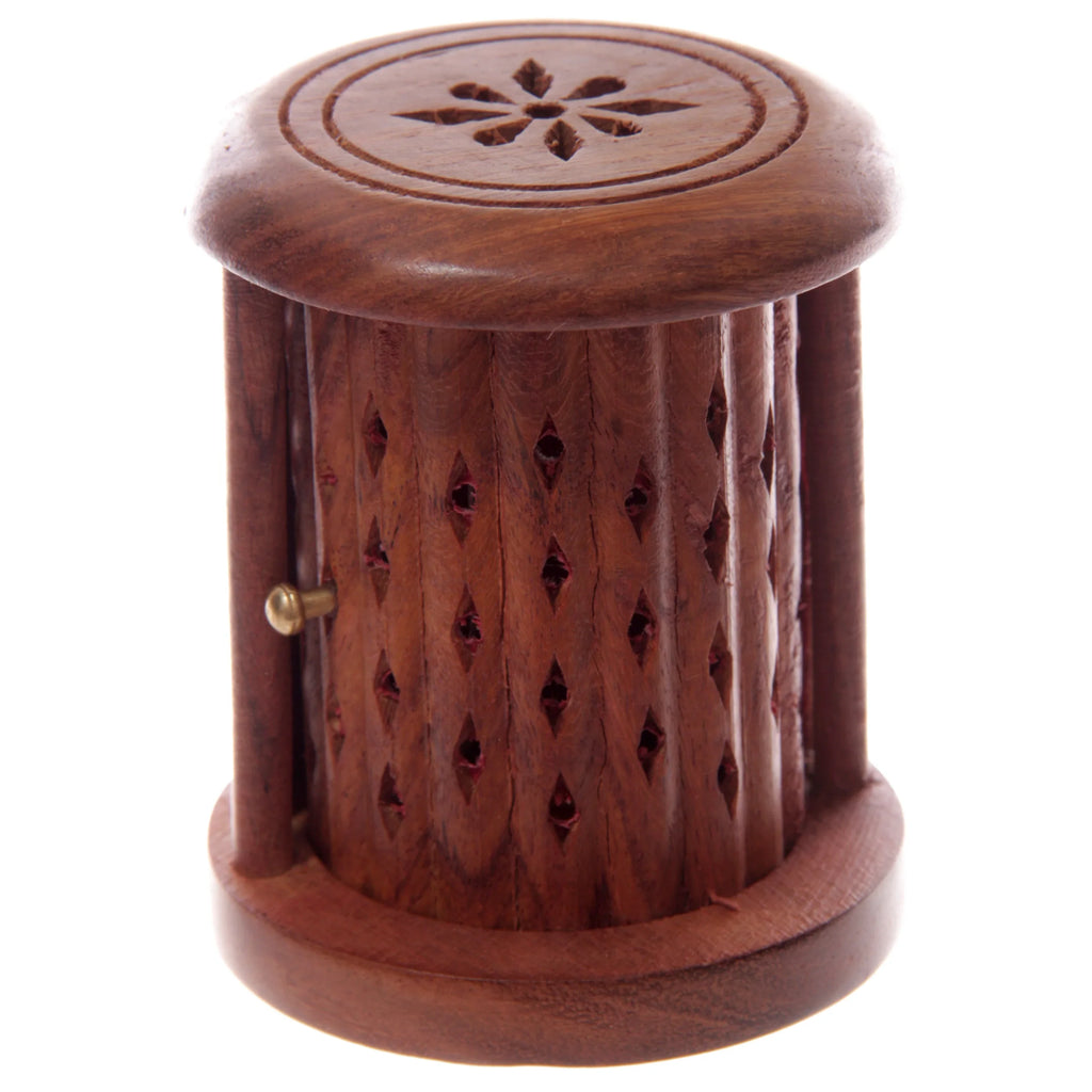 Angled view of a Sheesham wood carved barrel incense cone burner, featuring a floral design on its top and diamond-shaped perforations on the cylindrical body, with a small brass knob for the door.