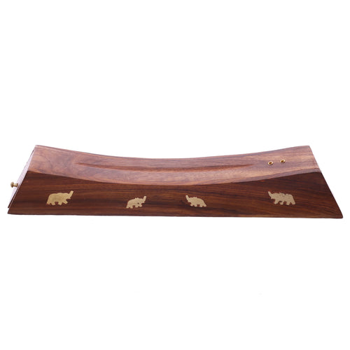 Angled view of a dark sheesham wood incense stick ashcatcher, featuring a curved surface with two brass-coloured holes and four brass-coloured elephant inlays along the front.