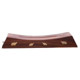 Angled view of a dark brown Sheesham wood incense stick ashcatcher, featuring a gently curved surface and four golden elephant inlays along its length. Two small brass-coloured holes for holding incense sticks are visible at one end.