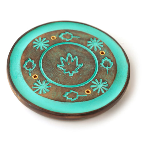 Angled view of a round mango wood incense holder ashcatcher, featuring distressed turquoise painted leaf and floral patterns, with gold-coloured holes for incense sticks and a central well for cones.