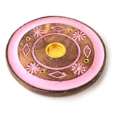 Angled top view of a round mango wood incense holder, featuring a pink painted floral and diamond design. This ashcatcher has a central gold-coloured cone burner and small holes for incense sticks.
