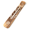 Angled view of a brown mango wood incense stick holder, featuring carved white designs including a prominent sun motif, a central feathered pattern, and star shapes, with a small hole for holding an incense stick and a channel for ash.