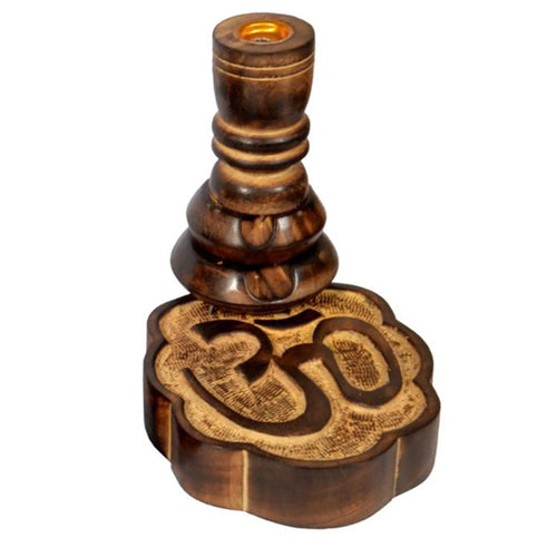 Angled view of a dark brown mango wood backflow incense burner, with a textured, carved Om symbol on its base and a tiered, sculpted pillar topped with a golden incense cone holder.