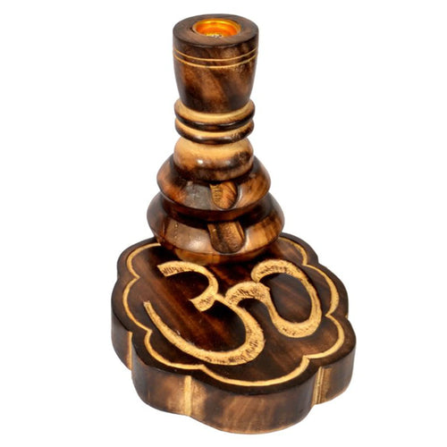 Angled view of a dark wooden backflow incense burner, showing its tiered column design, a gold-coloured metal cup at the top, and a carved Om symbol on the multi-petal base.