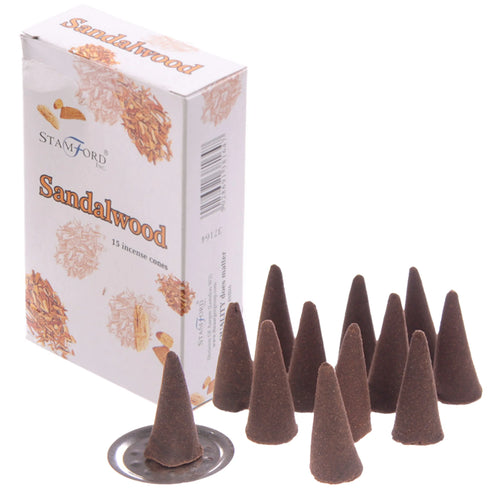 Angled view of a white box of sandalwood incense cones, labelled 'Sandalwood' and showing wood shavings. Alongside it are multiple dark brown conical incense cones, one resting on a small metallic holder.