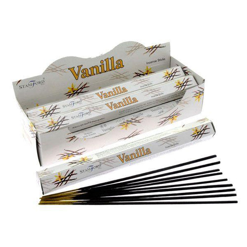 Angled view of a white display box containing multiple hexagonal packets of vanilla incense sticks, with one packet open and several black incense sticks fanned out.