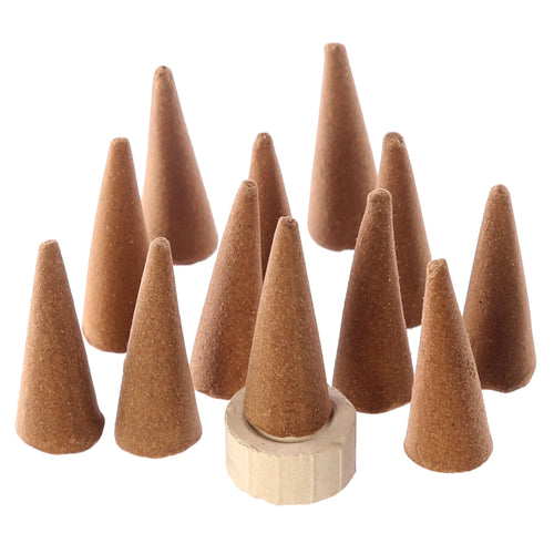 Angled view of a group of brown incense cones, showing their granular texture, with one cone placed in a light-coloured ceramic holder.