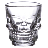 Front view of a clear glass skull shot glass, highlighting the moulded details of its eye sockets, nose, and teeth.
