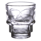 Front view of a clear glass shot glass shaped like a skull, showing its eye sockets and jawline.