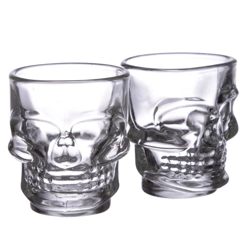 Angled view of two clear glass skull shot glasses on a white background.