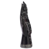 Small black mantric hand ornament, angled view, displaying intricate white patterns of stars, crescent moons, and a snake design along its side, with decorative bands on the fingers and wrist, against a white background.