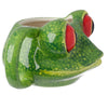 Angled view of a glossy green ceramic tree frog head mug with prominent red eyes and darker green speckles.