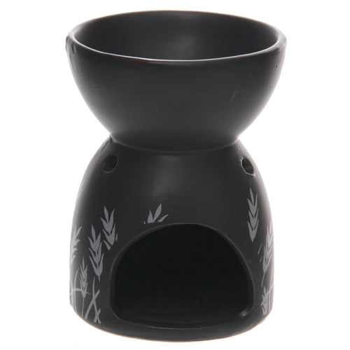 Angled view of a black ceramic oil and wax burner with a top bowl, featuring light grey grass designs on its base, a large opening for a tealight, and small ventilation holes.