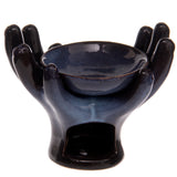 Angled view of an open hands ceramic oil burner in a dark blue, mottled glazed finish, with a central bowl and a tea light opening at the front.