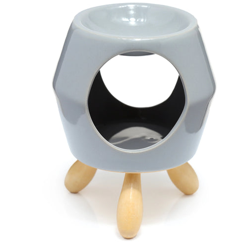 Grey ceramic oil burner with a faceted hexagonal body, a circular opening, and three light wooden feet, shown from an angled perspective.