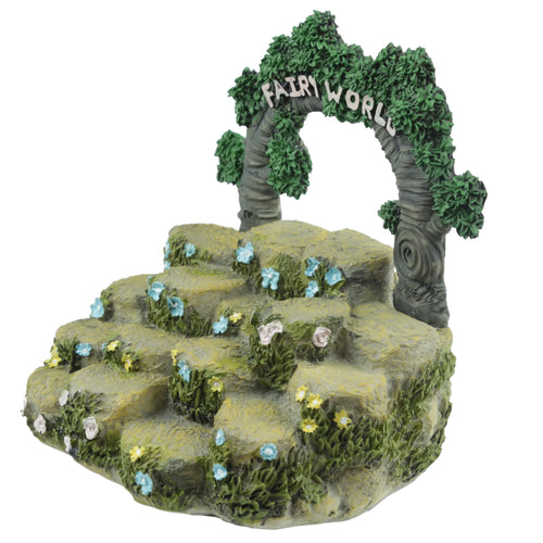 Angled view of a green and grey 'Fairy World' display stand, featuring tiered rock-like steps adorned with sculpted blue, yellow, and pink flowers and green moss. An archway formed by two leafy trees with 'FAIRY WORLD' text across the top stands at the rear.