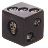 Close-up, angled view of a black, cube-shaped dice, featuring recessed light-coloured skull designs on its visible faces, showing markings for one, two, and three.