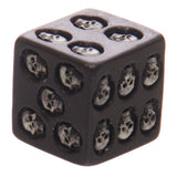 Angled close-up of a black dice, featuring white skull designs on its visible faces.