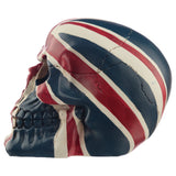 Side view of a gruesome Union Flag skull decoration, showing its left profile. It is painted in red, white, and blue, with a distressed finish and crack details.