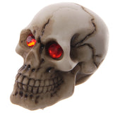 Angled view of a beige gruesome skull decoration with prominent red gem eyes and dark crack details.