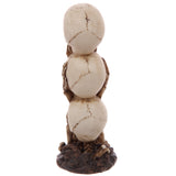 Rear view of a skull totem figurine, featuring three vertically stacked bone-coloured skulls, each displaying dark brown suture markings. The decorative ornament rests on a textured, dark brown base.