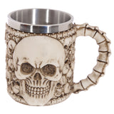 Front view of a cream and dark brown decorative multi-skull tankard, featuring a prominent skull emblem, a bone-effect handle, and a silver-coloured metal interior.