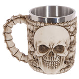 Front view of a decorative multi-skull tankard, featuring a large skull emblem on the front. The tankard has a bone-effect handle and a metal interior, presented in an aged bone colour.