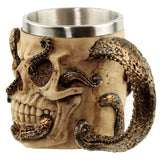 Angled view of a decorative tankard, showing a bone-coloured skull design with visible eye sockets, nasal cavity, and teeth, encircled by textured bronze octopus tentacles, one forming the handle, with a metallic stainless steel inner.