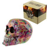 Angled view of a glossy, rainbow marble effect skull ornament with visible eye sockets and white teeth, placed next to its brown cardboard packaging box.
