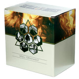 Angled view of the product box for a skull ornament. The off-white packaging features an abstract orange, brown, and green graphic with dark green hexagonal patterns displaying skull fragments, and 'SKULL ORNAMENT' text on the front.