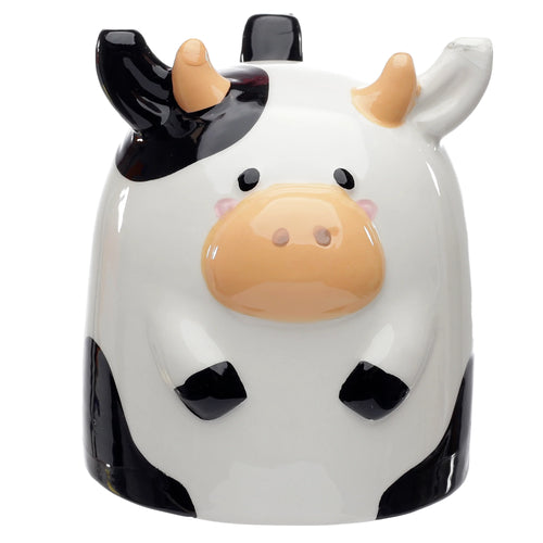 Front view of a ceramic upside down mug shaped like a white and black cow, with beige horns, black ears, a beige snout, black eyes, and pink cheeks.