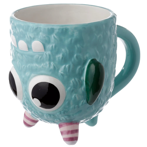 Angled view of a blue ceramic upside-down monster mug, depicting a textured body, large black and white eyes, white teeth, a dark green ear, and pink and white striped feet at the base.