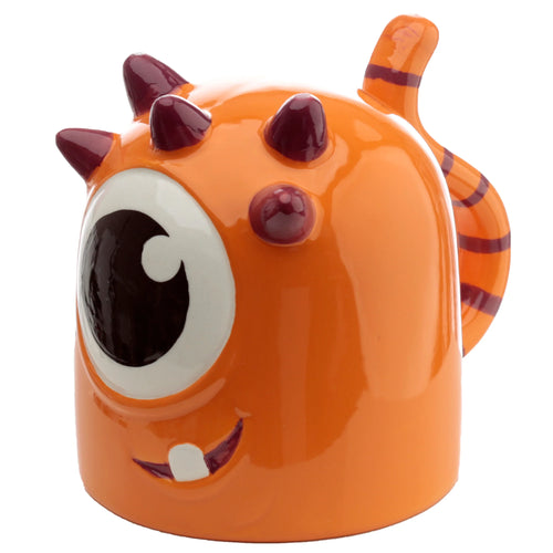 Angled view of an orange monster-shaped ceramic upside down mug, featuring a large single eye, a purple-lipped smile with one white tooth, dark purple horns, and a striped tail handle.
